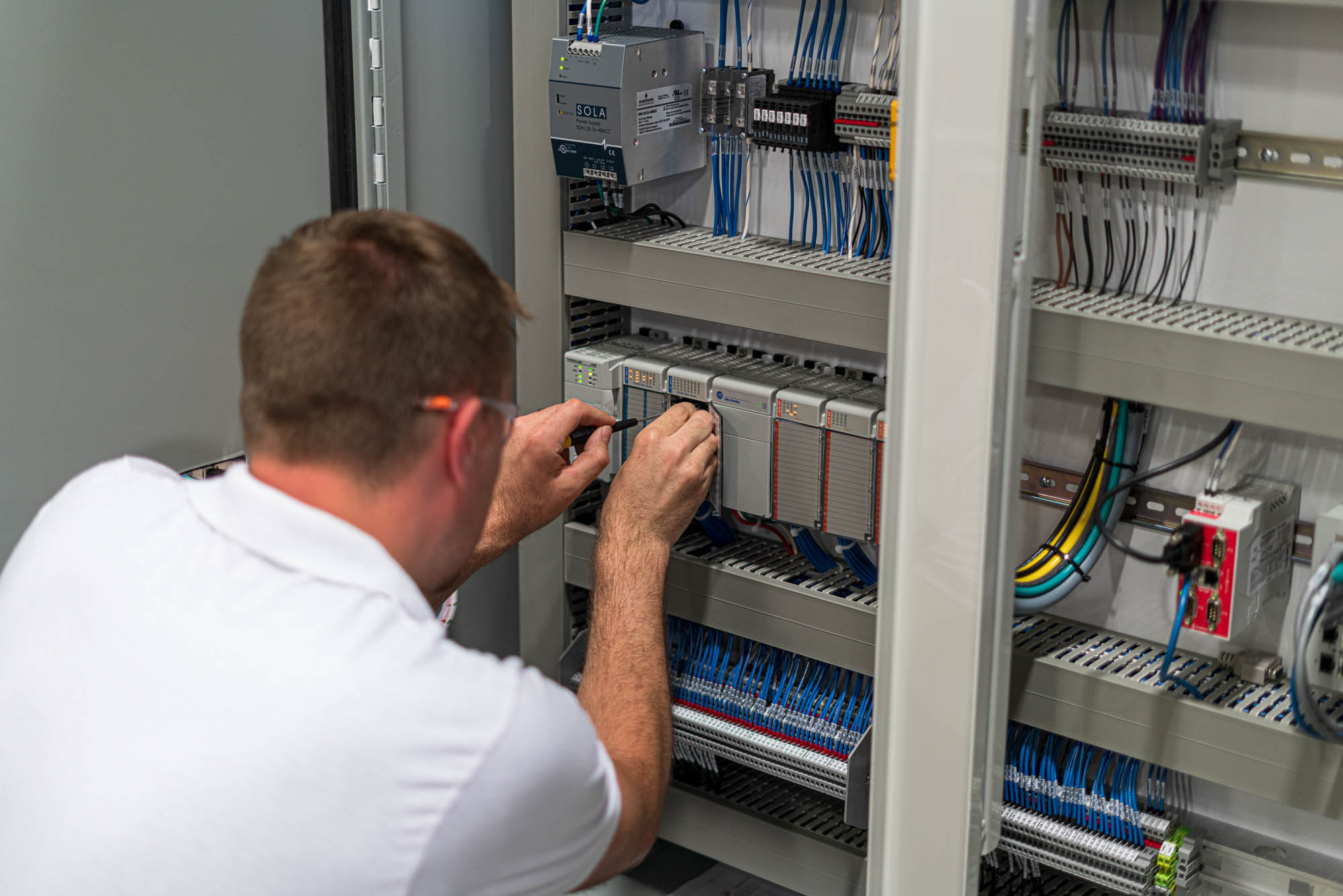 Ahaus employee working inside an automation control panel full of controller components and wires.